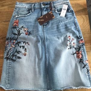 Adorable denim skirt with distressed detail and floral embroidery.